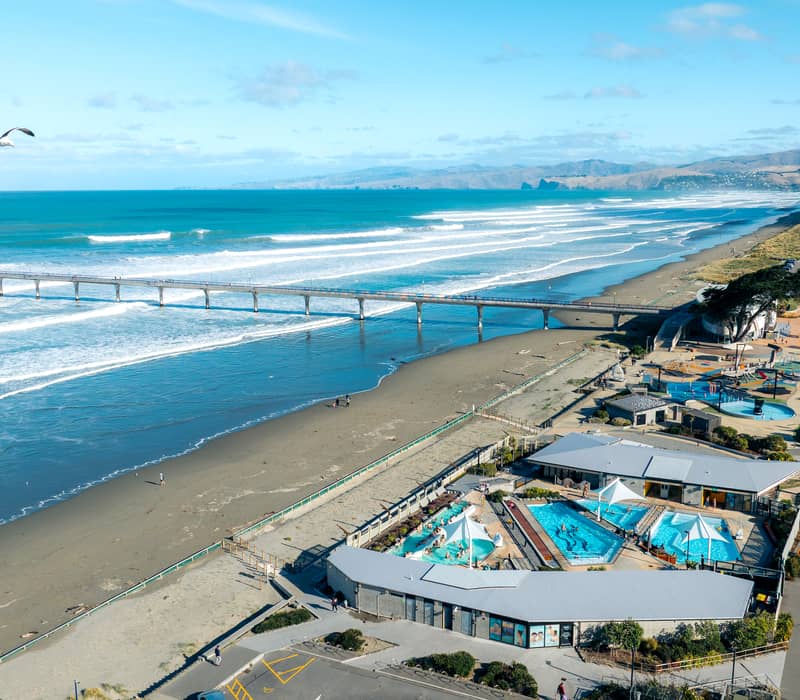 Aerial view of New Brighton Pier and the turquoise hot pools on the Christchurch coast.