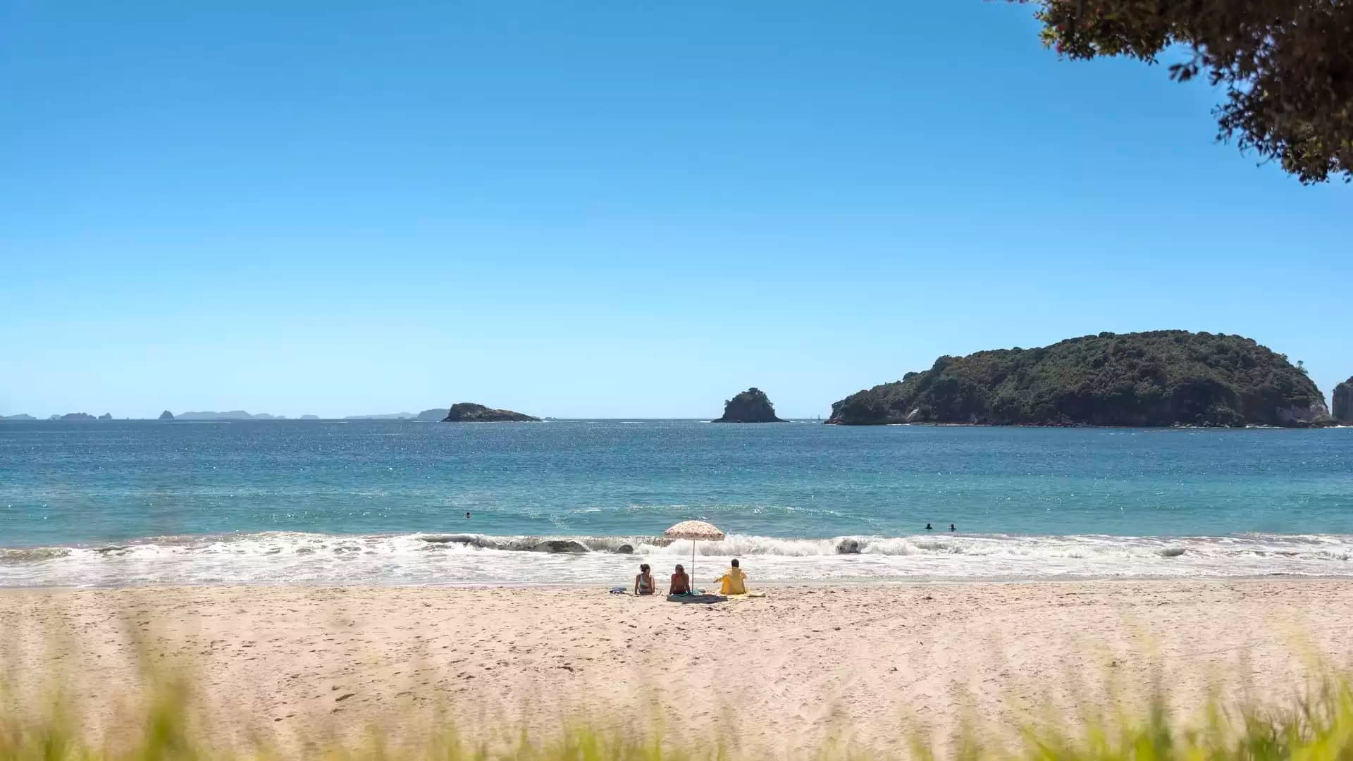 Couple relaxing on warm sand of Hahei Beach Coromandel.