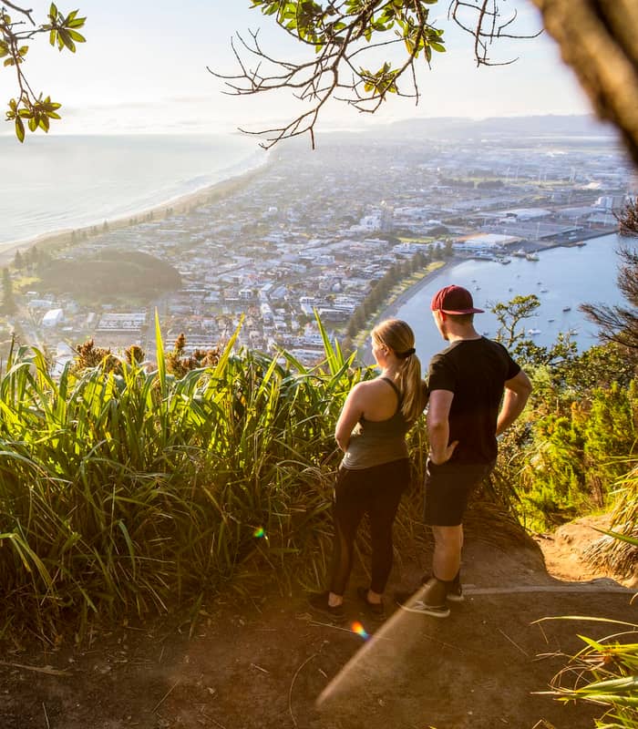 Couple looking at view of Mount Maunganui township from the Mount walking track. 