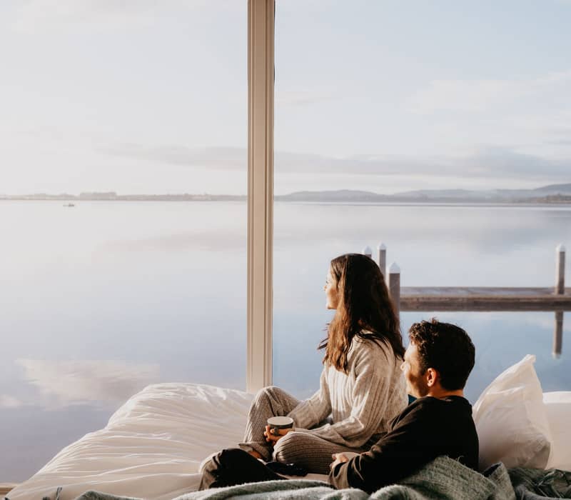 Couple looking out at view from Trinity Wharf hotel. 