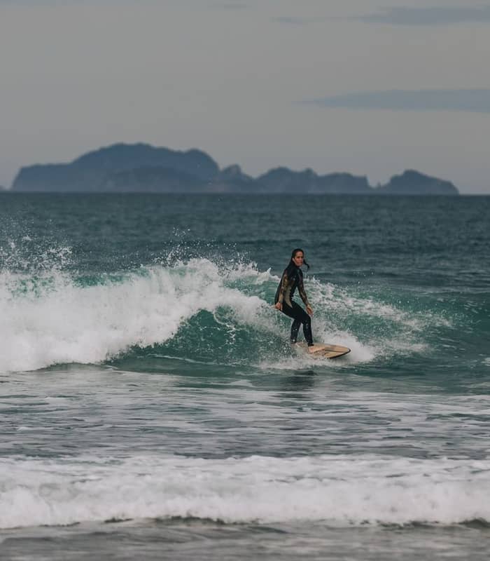 Woman surfing in waves in Coromandel.