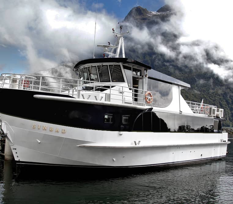 Sinbad ferry boat docked at Milford Sound with mountains and clouds in the background. Credit: Real Journeys