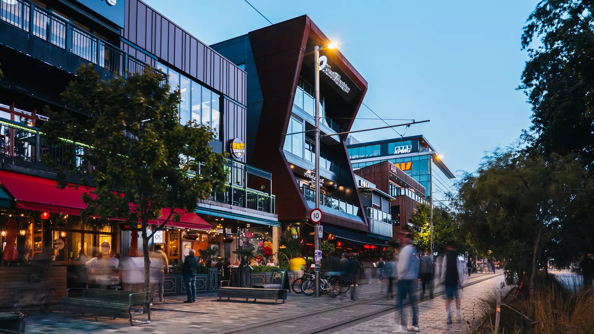 A busy street scene at dusk on Oxford Terrace in Christchurch, featuring glowing restaurants and modern architecture. Credit: Christchurch NZ