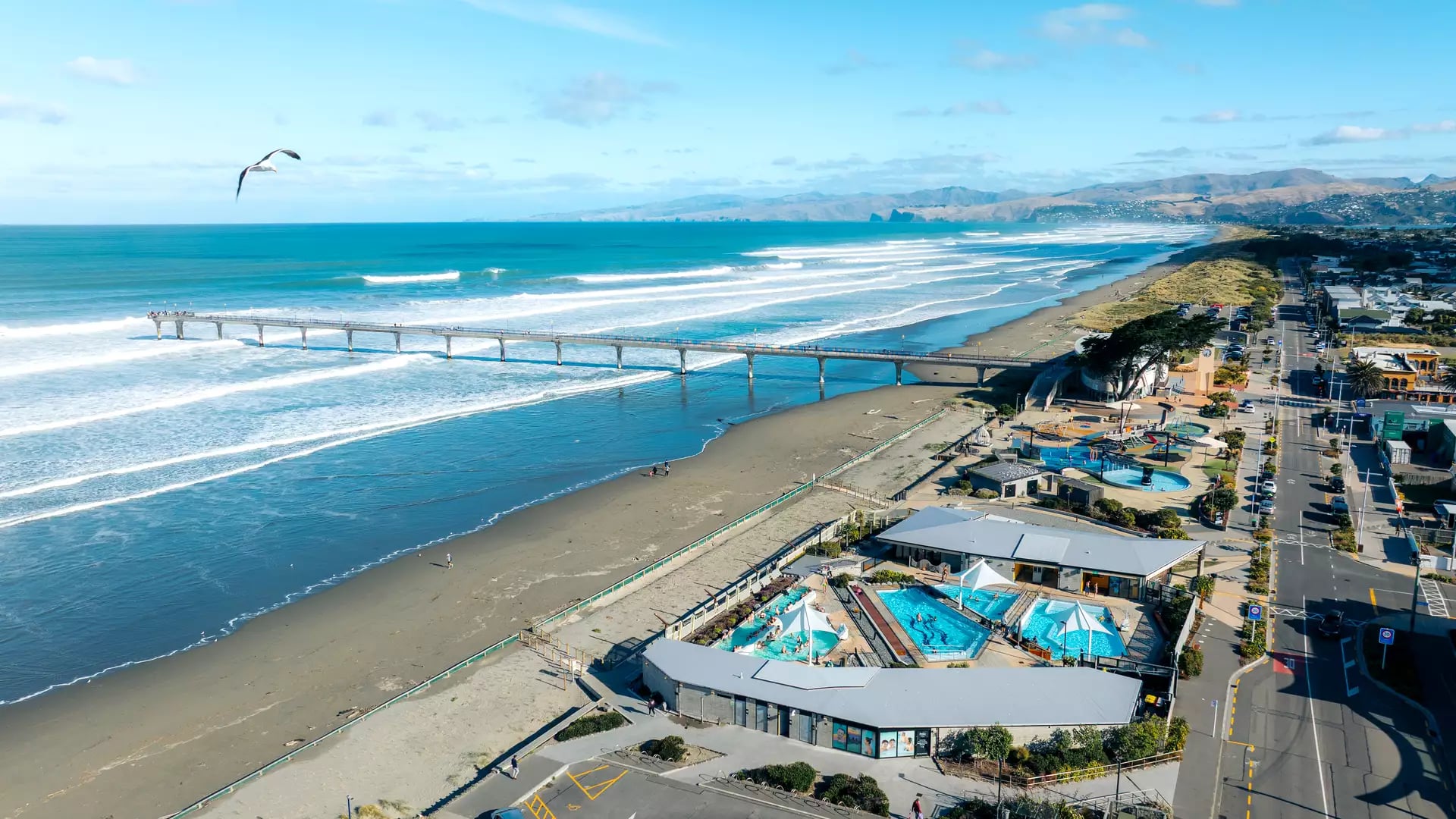 Aerial view of New Brighton Pier and the turquoise hot pools on the Christchurch coast.