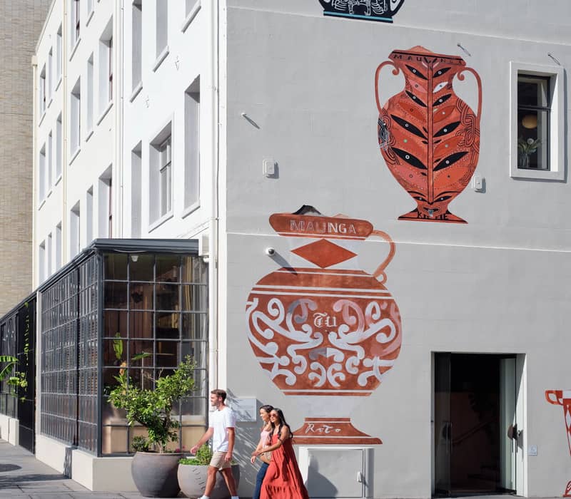 Close-up of street art mural on Britomart building with pedestrians walking past