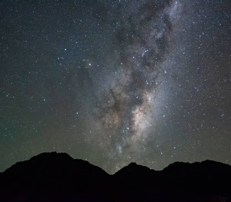 Milky Way galaxy with stars over dark mountain silhouettes at night.