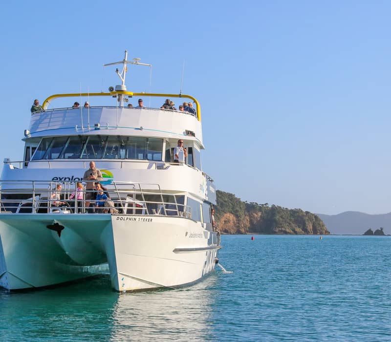 Tour boat cruising through the Bay of Islands with passengers onboard.
